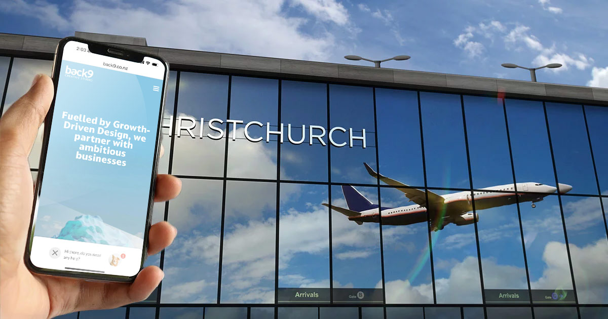 Image-of-a-mock-up-of-a-person-holding-phone-with-Back9-Creative-website-on-screen-in-front-fo-Christchurch-Airport-terminal